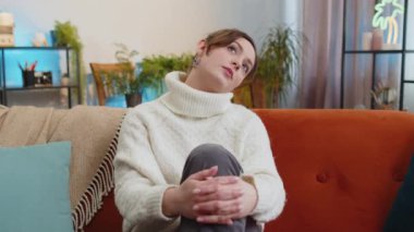 Sad lonely young woman sitting at home room looks pensive thinks over life concerns or unrequited love suffers from unfair situation. Alone girl problem break up, depressed feeling bad annoyed burnout