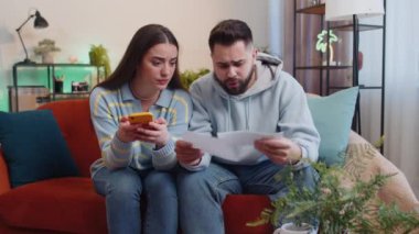 Stresli genç aile evliliği. Ödenmemiş banka borçlarına bakan erkek kadın evli. Evrak işleri, planlama bütçesi, ipotek ödemelerini hesaplamak. Karı koca eve kağıt para atıyor.
