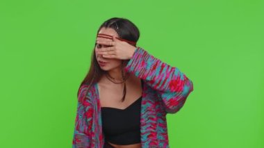 Meraklı, genç bir kadın elleriyle gözlerini kapatıyor ve parmaklarının arkasına saklanıyor. Gözetleyerek uzaklarda bir şeyler arıyor. Yeşil krom anahtar arka planındaki kız