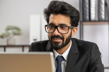 Yakın plan bir portre, Hintli sakallı iş adamı ev ofisinin iş yerinde dizüstü bilgisayarla çalışan serbest çalışan biri. Menajer serbest çalışan Hintli adam defter üzerinde çalışıyor. Mesaj gönderiyor, internetten alışveriş yapıyor.