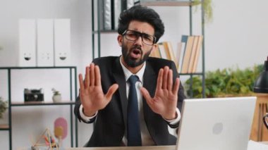 Stop. Indian businessman guy working on laptop, warning of finish, prohibited access, declining communication, body language, rejection, danger trouble. Manager man freelancer at home office workplace