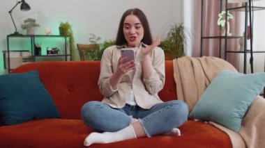Aman Tanrım. Vay canına. Heyecanlı mutlu, neşeli genç kadın akıllı telefon daktilo kullanıyor. Kazanan kazanır. Zaferi kutlar. Cep telefonlu bir kız, evinde, odasında, kanepede oturuyor.