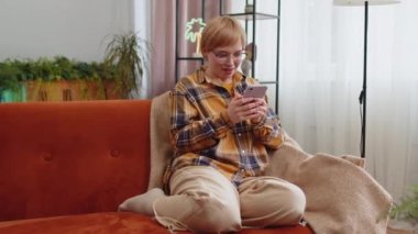 Mutlu genç bir kadın cep telefonu daktilosu kullanıyor ve 