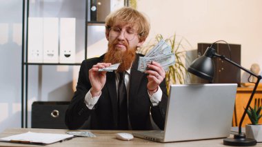 Zengin patron işadamı, hayran başarısı, piyango kazananı, büyük gelir ve servet gibi nakit para banknotları sallıyor. Genç sakallı adam iş yerinde serbest çalışıyor.