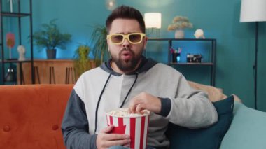 Üç boyutlu gözlüklü heyecanlı genç adam kanepede oturup patlamış mısır yiyor ve evde ilginç TV dizileri, spor oyunları, filmler, çevrimiçi sosyal medya filmi içerikleri izliyor. Eğlenen adam