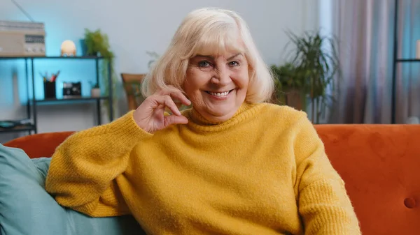 stock image Happy calm senior woman at home couch smiling friendly, glad expression looking away dreaming resting, relaxation feel satisfied concept good news, celebrate win. Elderly grandmother in living room