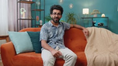 Mutlu Hintli adam bağırıyor, başarıyı kutluyor, kazanıyor, gol başarısı, iyi haber, piyango şansı, zafer, modern ev dairesinde televizyon şampiyonluğu seyrediyor. Hindu adam oturma odasında kanepede oturuyor.