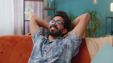 Yorgun Hintli adam rahat kanepeye uzanıp dinleniyor, gündüz uyukluyor. Kafasının arkasında el ele tutuşan kaygısız Hintli adamın portresi. Evde kanepede uyuyakalıyor.