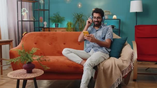 Happy Overjoyed Hindu Indian Man Wireless Headphones Relaxing Sits Couch — Stock videók