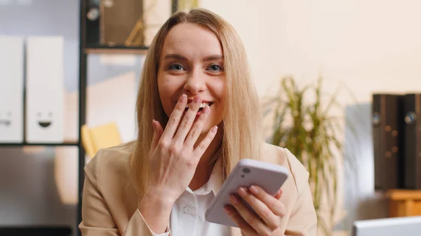 Oh my God, Wow. Happy amazed young businesswoman working on smartphone shocked by sudden victory, game winning, lottery goal achievemen, good news. Blonde manager woman girl freelancer at home office