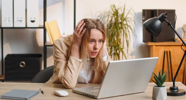 Dizüstü bilgisayar üzerinde çalışırken şok olmuş genç bir iş kadını, beklenmedik internet sitesi sorunu, bilgisayar virüsü veri kaybı. Freelancer ofisteki kırık defter yüzünden kızgın.
