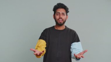 Neden? Öfkeli bir ifadeyle el kaldıran samimi, asabi Hintli adam başarısızlığının nedenini sorar. Tehlikenin huzursuzluğunu gösterir. Gri arka planda kafası karışmış yakışıklı Hintli adam.