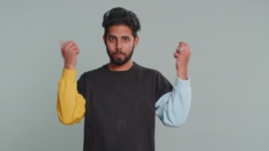 Genç Hintli adam boşa harcıyor, etrafa para saçıyor, daha fazla bahşiş, büyük kar, piyango ikramiyesi, başarılı alışveriş ödemeleri, nakit para. Hintli adam gri arka planda izole edilmiş.