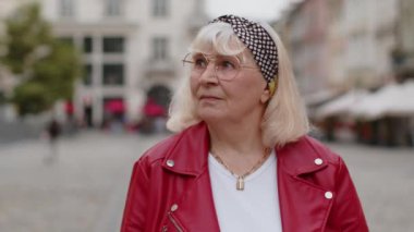 Yaz günlerinde şehir sokaklarında gezen yaşlı kadın turistin portresi. Yaşlı gezgin büyükanne gülümsüyor ve dışarıda keyif çatıyor. Kasaba yaşam tarzları, tatil