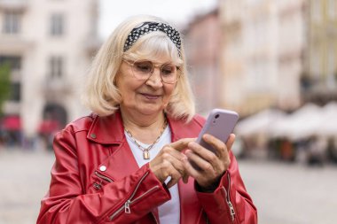 Gezici navigatör uygulamasında haritada bir yol bulmak için akıllı telefon kullanarak mesajlar yazan son sınıf kadınının portresi. Şehir sokaklarında yürüyen yaşlı bir büyükanne. Kasaba yaşam tarzları