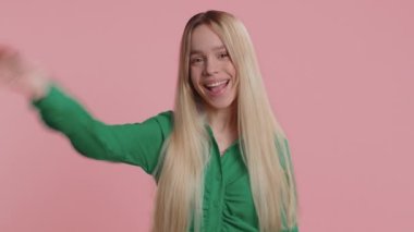 Buraya gel, bize katıl. Hoş geldiniz. Genç bir kadın elleriyle davetkar bir jest yapıyor. Katılmak istiyor. Gelmeye davet ediyor. Beyaz kız pembe stüdyo arka planında izole edilmiş.