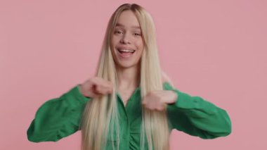 Ben en iyisiyim, beni seç. Genç, heyecanlı, beyaz kadın kazanan kendini göstermekten gurur duyuyor, kendine güvenen, başarıdan aşırı mutlu görünüyor. Stüdyo pembe arka planda izole edilmiş güzel yetişkin bir kız.