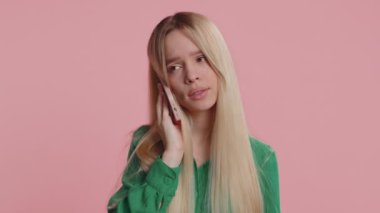 İlgisiz beyaz bir kadın akıllı telefonda can sıkıcı konuşmalar yapıyor. Uykulu yetişkin kız arkadaşıyla cep telefonuyla konuşuyor, stüdyoda pembe arka planda çevrimiçi konuşmalar yapıyor.