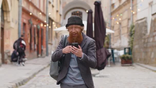 Ung Skægget Mand Bruger Mobil Smartphone Fejrer Vinde Gode Budskab – Stock-video
