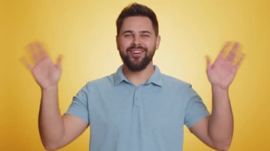 Buraya gel, bize katıl. Hoş geldiniz. Genç sakallı adam elleriyle davetkar bir jest yapıyor. Katılmak istiyor. Gelmeye çağırıyor. Beyaz adam sarı stüdyo arka planında izole edilmiş.