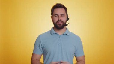 Kulaklık takan gülümseyen genç adam, serbest çalışan, çağrı merkezi ya da destek operatörü yardım hattı, müşteriyle ya da meslektaşıyla konuşmak, iletişim desteği. Sarı arka planda izole adam