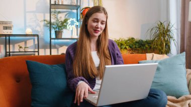 Kanepede oturmuş kameraya bakan genç bir kadın arkadaşlarıyla ya da ailesiyle görüntülü bir konferans görüşmesi yapıyor ve hoş sohbetin tadını çıkarıyor. Sınıfta el sallayarak gülen güzel kızın portresi.