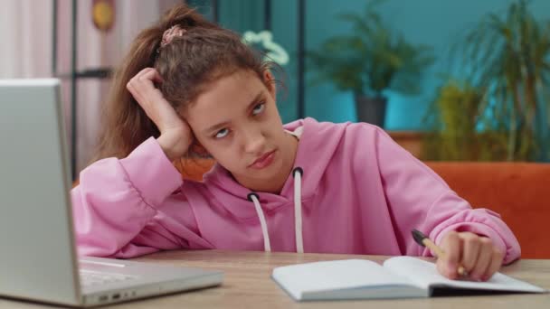 疲惫的白人学龄前女学生在网上做家庭作业 在笔记本电脑上打字 在笔记本上记笔记 远程学习教育 在家里工作的小孩坐在桌旁 — 图库视频影像