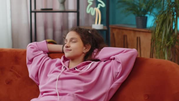 快乐疲惫的学龄前女学生躺在橙色的沙发上休息 享受白天的小睡 无忧无虑的小孩打盹 睡在家里客厅的沙发上 枕着枕头 — 图库视频影像