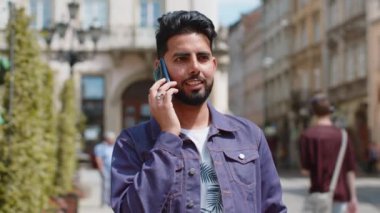 Mutlu sakallı adam uzaktan iletişim kurarak akıllı telefondan konuşuyor. Yakışıklı, genç Hintli adam telefonda konuşuyor. Şehir caddesinde beklenmedik bir dedikodu dolaşıyor. Şehir yaşam tarzları açık havada