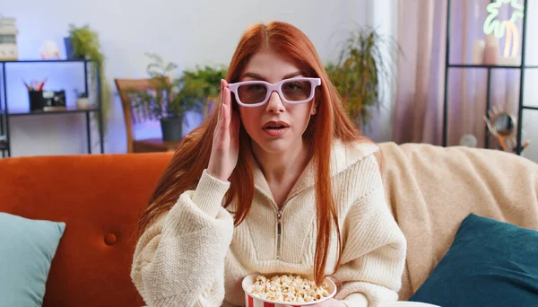 興奮した若い女性がソファに座ってポップコーンを食べ 自宅で面白いテレビシリーズ スポーツゲーム オンラインソーシャルメディア映画コンテンツを見ています 3Dメガネで女の子は国内エンターテイメントを楽しんで — ストック写真