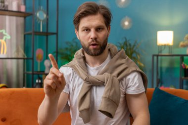 Hoşnutsuz berbat bir fikre tepki veren mutsuz bir adam, kötü kaliteden memnun olmayan, el sallayan, başını sallayan hayır, reddet fikri, evlenme teklifini sevme. Evdeki kanepede oturan genç beyaz adam.