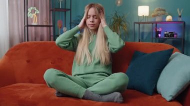 Baş ağrısı problemini tedavi etmek için tapınakları ovuşturan hoşnutsuz bir kadın, tansiyon ve migrenden muzdarip, evde acı içinde kıvranan yüksek tansiyon. Kanepede beyaz bir kız. Yaşam Tarzları