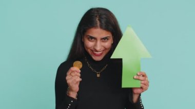 Hintli bir kadın elinde altın bitcoin, kripto para yatırımı ve BTC para bozdurma artışını gösteren bir ok işareti tutuyor. Başarılı gelişme gösteren kız ortaya çıkıyor