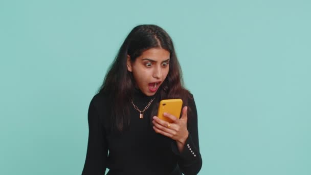 印度女人期待智能手机展示真诚的喜悦胜利 收到钞票钞票 成功彩票头彩好运 收入薪水工资 被隔离在蓝色背景下的印度教女孩 — 图库视频影像