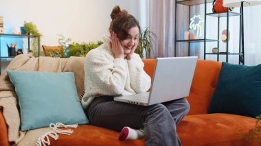 Aman Tanrım. Vay canına. Laptop bilgisayarı kullanan genç bir kadın, iyi haber mesajı alıyor, ani zaferi kutluyor piyango galibiyetini evde online alışveriş yaparak kutluyor. Yaşam tarzı teknolojileri