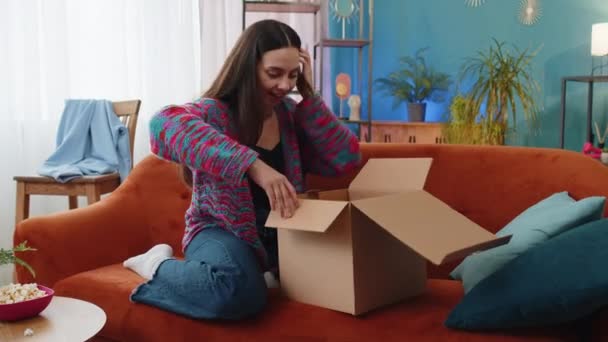 快乐的年轻女人坐在家里整理送货包裹 笑容满面的白种人女购物者 网上商店的顾客打开纸板箱 接受快速邮寄的购物礼物 — 图库视频影像
