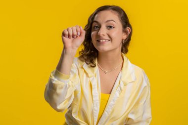 Kim var orada? Tık-tık. Heyecanlı genç bir kadın kapıyı çalıp kimin evde olduğunu soruyor, utanıyor, hiçbir fikri yok, bilgisiz ve kararsız. Stüdyo sarı arka planda tek başına kalmış bir kız.