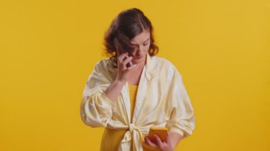 Sinirli, stresli genç bir kadın iki cep telefonuyla bağırarak konuşuyor. Tartışıyorlar. Şikayet anlaşmazlığı çözülüyor. Sarı stüdyo arka planında izole kız