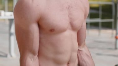 Yakın plan atletik üstsüz kaslı adam kol ağırlığı kaldırıyor halter egzersizleri yapıyor, kol kaslarını şişiriyor. Çocuk parkındaki adam. Spor fitness rutini, vücut geliştirme çalışması. Kuvvet motivasyonu