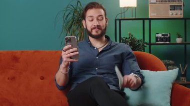 Aile bütçesi planlamak. Gülümseyen Lübnanlı adam nakit sayıyor. Akıllı telefon kullanıyor. Ev faturalarını hesaplıyor. Neşeli Arap adam gelirinden memnun ve planlı tatil hediyeleri için para biriktiriyor.
