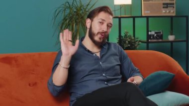 Hoş geldiniz. Lübnanlı adam kameraya dostça gülümsüyor ve el sallıyor merhaba, merhaba, merhaba ya da güle güle, evde misafirperver bir ifadeyle karşılıyor. Arap adam oturma odasında kanepede oturuyor.