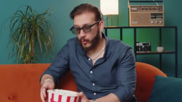 3Dメガネで興奮したレバノン人男性は ソファに座ってポップコーンスナックを食べ 自宅のアパートで面白いテレビシリアルスポーツゲーム映画オンラインソーシャルメディア映画コンテンツを見ています エンターテイメントを楽しむ男 — ストック動画