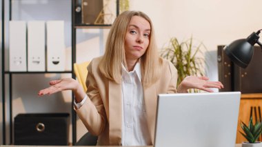 I dont know what to say. Confused business woman working on laptop at office workplace. Freelancer feeling embarrassed about ambiguous question, having doubts, no answer idea, being clueless uncertain