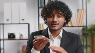 Sakallı Hintli iş adamı ofis masasında dizüstü bilgisayarla cep telefonu hoparlörü ile konuşuyor. Menajer serbest çalışan Hintli adam haberci sohbet uygulamaları kullanarak akıllı telefon tutuyor. İstihdam, meslek
