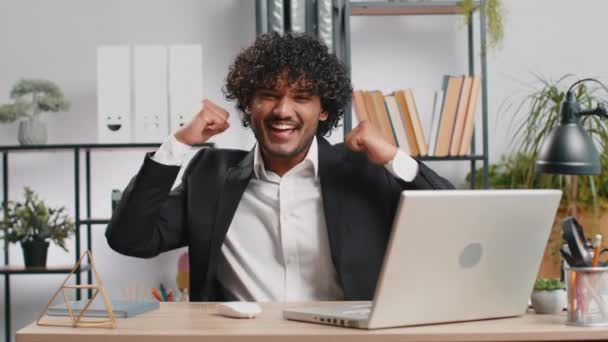 在笔记本电脑上工作的快乐而惊奇的印度商人被突如其来的胜利 游戏的胜利 彩票目标的实现者 好消息震惊了 在总部办公室工作的兴奋的经理 自由职业者 — 图库视频影像
