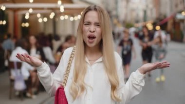 - Ne? - Neden? Şaşırmış sarışın genç bir kadın başarısızlığın sebebini sorarak el kaldırıyor, dışarıda yaşanan sorunlardan kuşkulandığını gösteriyor. Şehir caddesinde kafası karışmış genç kız yürüyor.