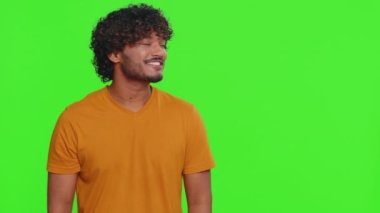 Genç Hintli adam başparmağını kaldırıyor ve boş bir yeri işaret ediyor. Ticari metinler için reklam alanı, ürün tanıtımı için kopyalama alanı. Sakallı Hintli adam yeşil krom anahtar arka planda kapalı alanda izole edilmiş.