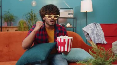Üç boyutlu gözlüklü heyecanlı Hintli adam kanepede oturup patlamış mısır yiyor ve TV 'de ilginç bir spor maçı izliyor, sosyal medya içerikli çevrimiçi bir film izliyor. Eğlenen adam