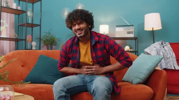 Ung Indian Man Liggande Soffan Känsla Plötslig Stark Buken Ont — Stockvideo