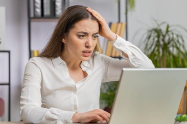Laptop üzerinde çalışırken asabi Kafkasyalı iş kadını, beklenmedik internet sitesi sorunu, bilgisayar virüsü veri kaybı. Freelancer ofisteki iş yerinde kızgın, kırık bir defter gibi hissediyor.